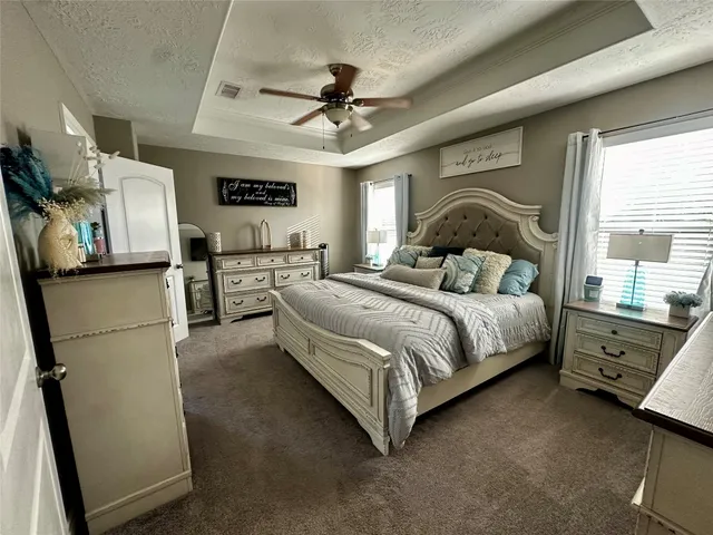 a bedroom with a bed dresser and a large window