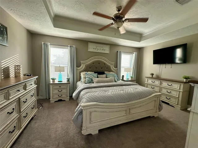 a bedroom with a large bed and a flat tv screen on dresser