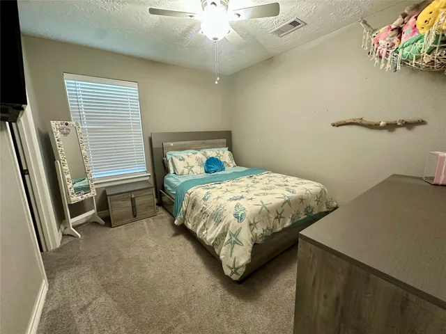 a bedroom with a bed and a flat tv screen on dresser