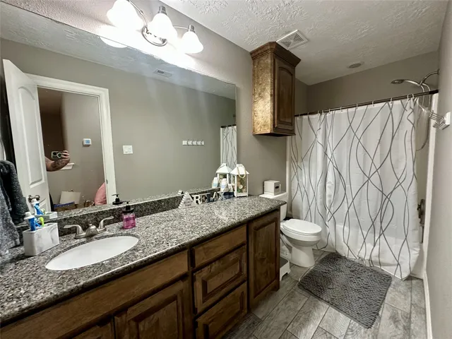 a bathroom with a granite countertop sink toilet and a mirror