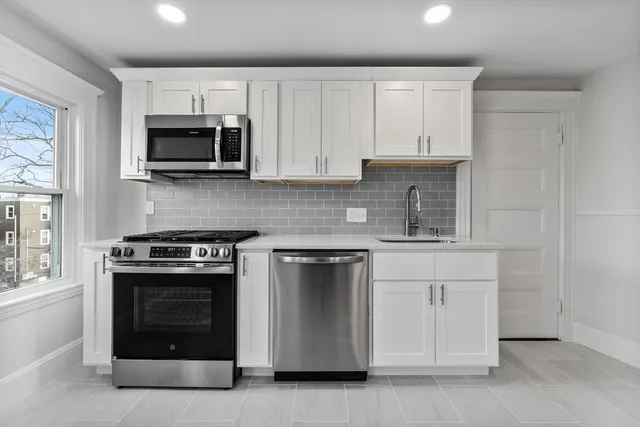 a kitchen with white cabinets and stainless steel appliances
