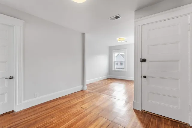 a view of a hallway with wooden floor and a bathroom