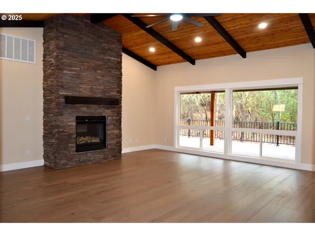 a view of an empty room with wooden floor and a fireplace