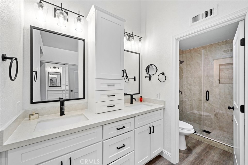 13615 Almond Street Tustin, CA 92782 - Photo 23 of 54 a bathroom with double vanity sinks a toilet a mirror and shower