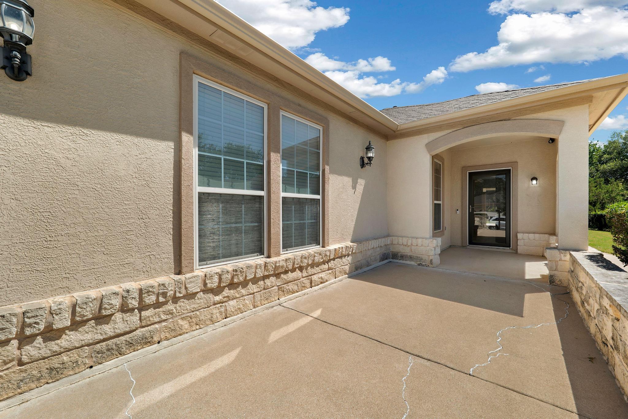 520 Mill Pond Path Georgetown, TX 78633 - Photo 8 of 38 A welcoming concrete patio invites entry, framed by textured stucco walls and a charming stone veneer foundation.