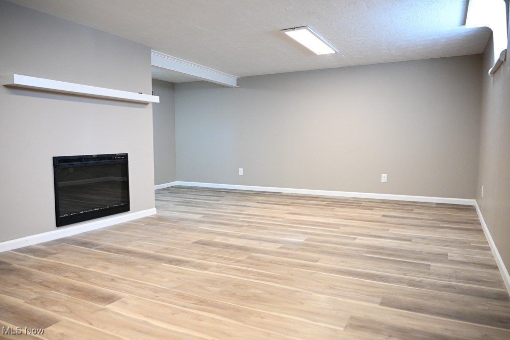 2284 Traymore Road Cleveland, OH 44118 - Photo 18 of 19 Finished below grade area with light wood-type flooring, baseboards, and a glass covered fireplace