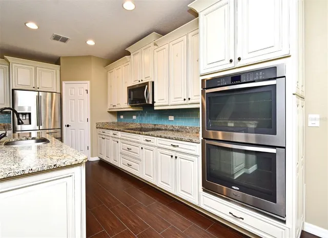 a kitchen with granite countertop white cabinets stainless steel appliances and a sink