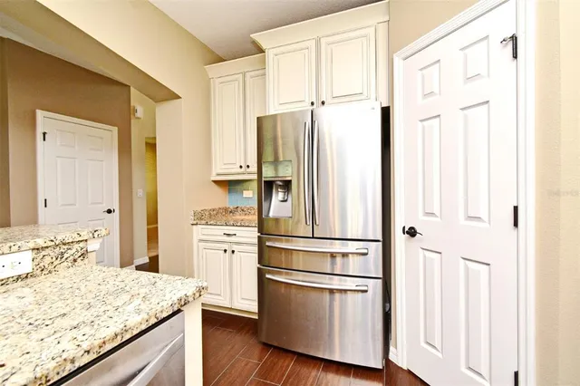 a kitchen with stainless steel appliances granite countertop a refrigerator and white cabinets