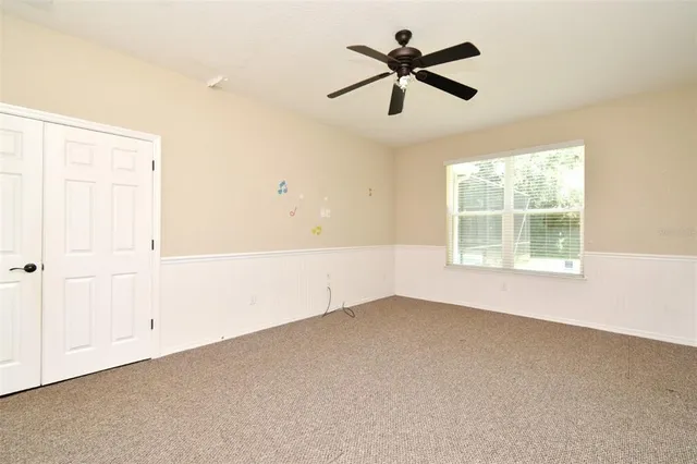 an empty room with a window and a ceiling fan