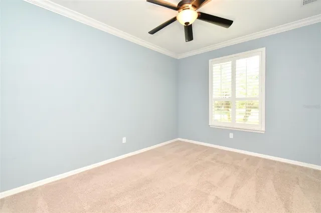 an empty room with a ceiling fan and carpet
