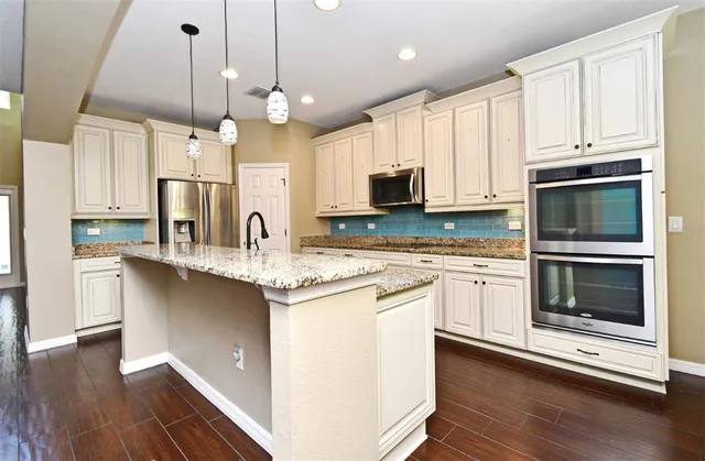 a kitchen with stainless steel appliances granite countertop a sink a stove and a refrigerator