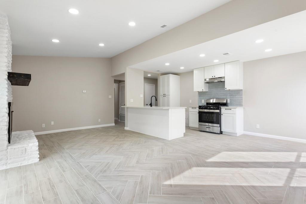 9604 Crown Ridge Road Austin, TX 78753 - Photo 8 of 24 Herringbone tile flooring anchors an open-concept living space with a contemporary kitchen and a charming brick fireplace.