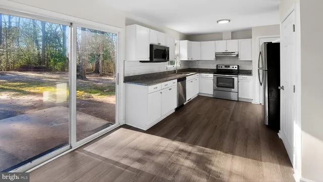 a kitchen with granite countertop a refrigerator a stove top oven a sink and a large window