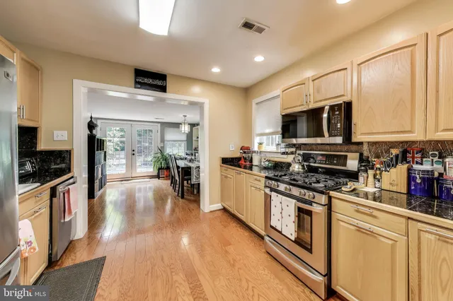 a large kitchen with stainless steel appliances lots of counter space and wooden floor