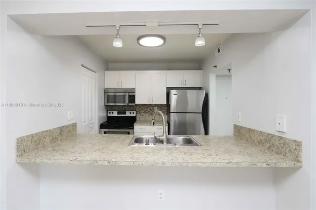 a kitchen with kitchen island a refrigerator sink and stove