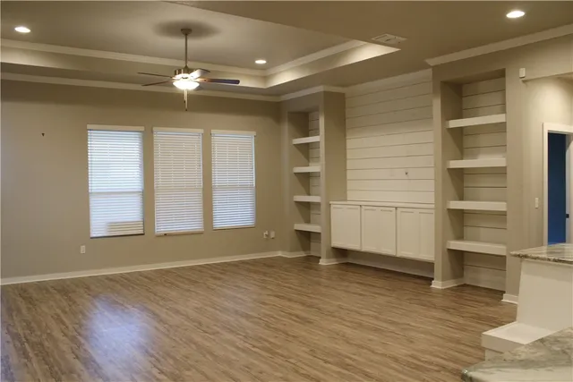 a view of empty room with wooden floor and fan