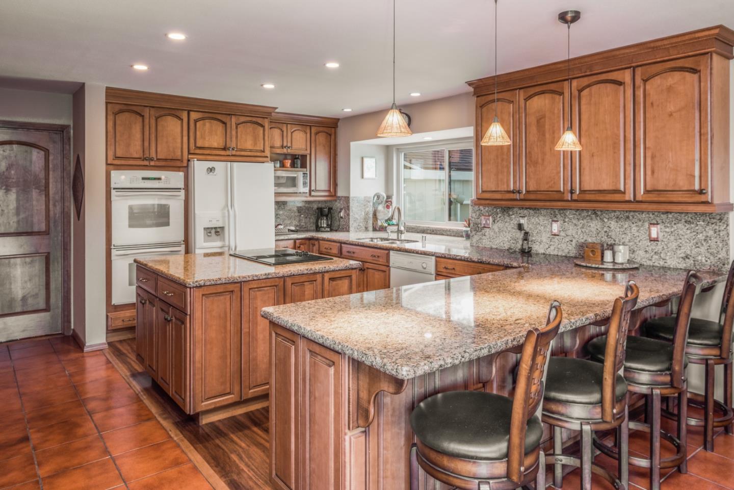 12765 Sundance Lane Carmel Valley, CA 93924 - Photo 11 of 43 a kitchen with granite countertop a table chairs microwave and refrigerator