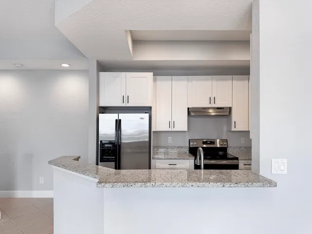 a kitchen with stainless steel appliances granite countertop a sink a stove and a refrigerator