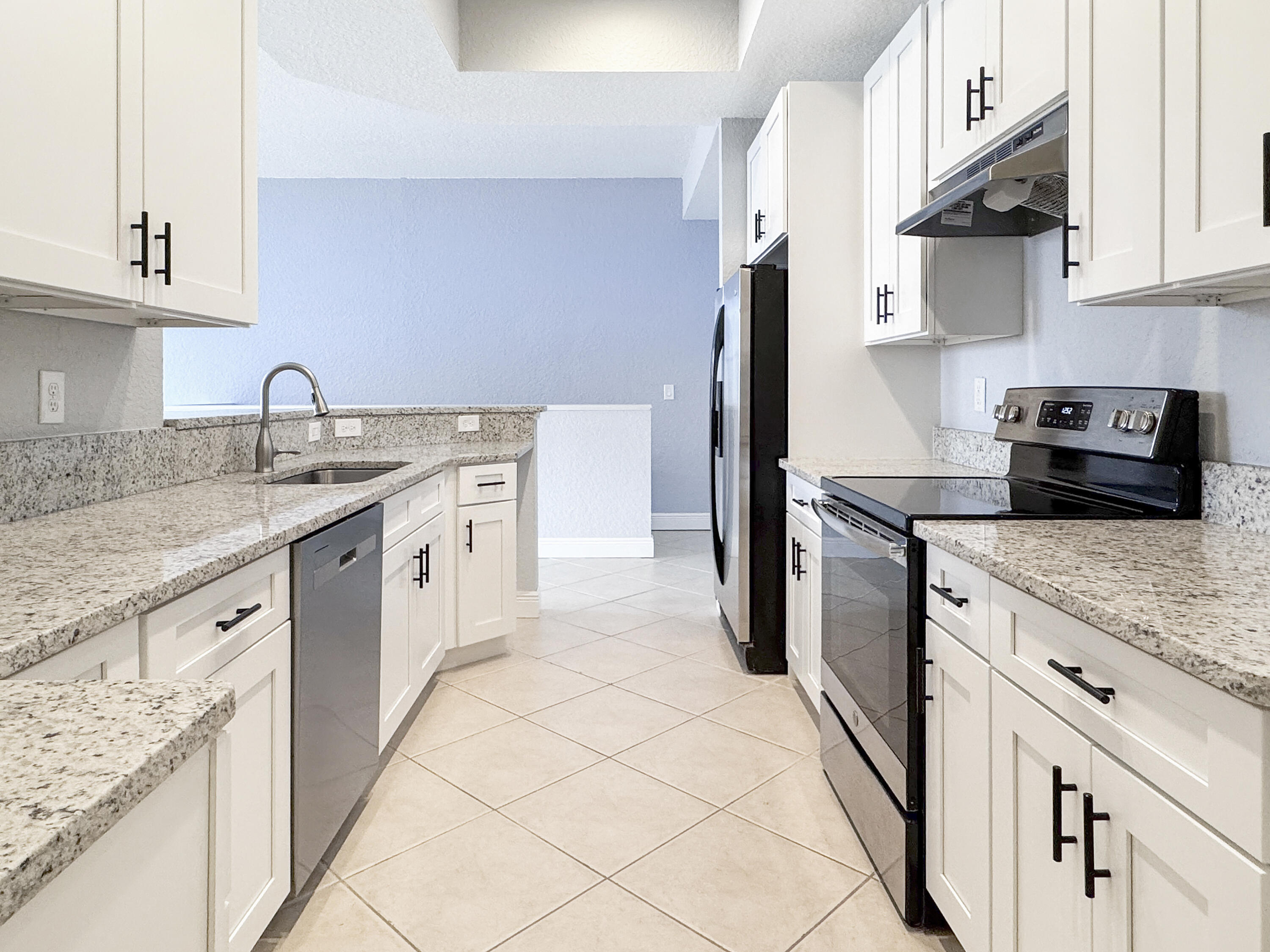 10560 Southwest Stephanie Way, Unit 1206 Port St. Lucie, FL 34987 - Photo 5 of 23 a kitchen with stainless steel appliances granite countertop a sink stove and refrigerator