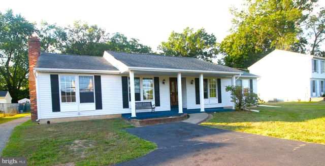a view of a white house with a large garden and large trees