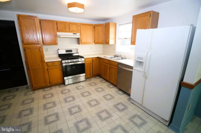 a kitchen with granite countertop a refrigerator stove top oven and sink