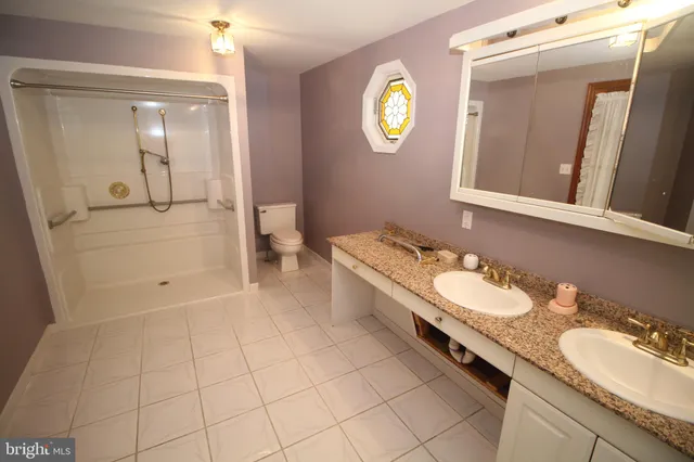 a spacious bathroom with a granite countertop sink and a mirror
