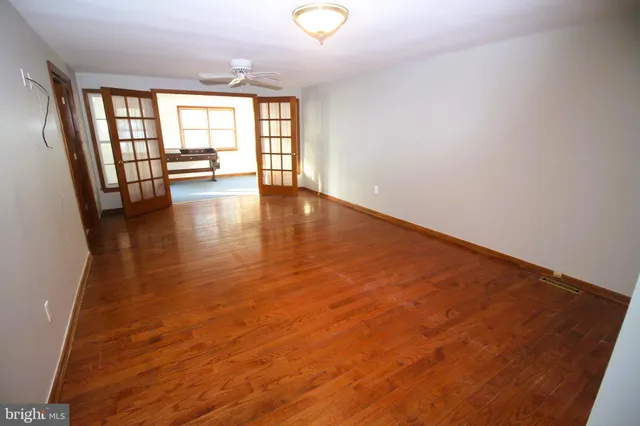 an empty room with wooden floor and windows