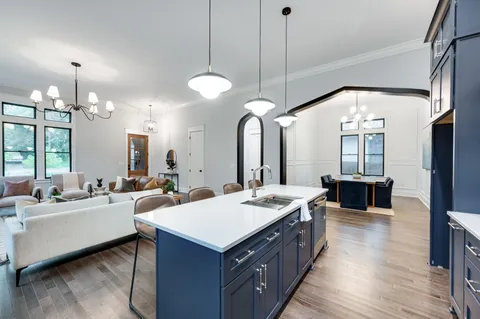 a large kitchen with kitchen island a sink a counter space appliances and living room view