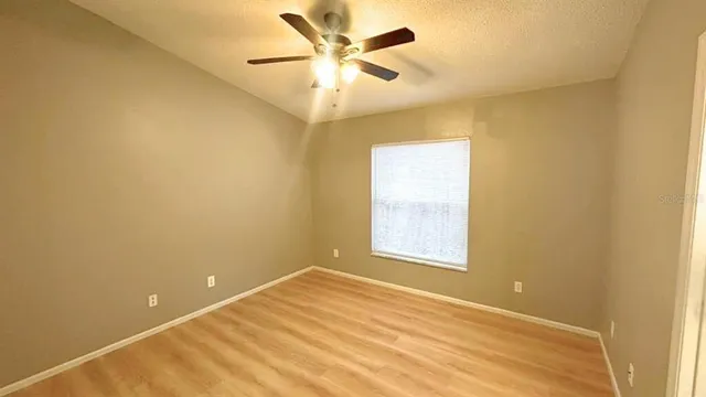 an empty room with a window and a ceiling fan