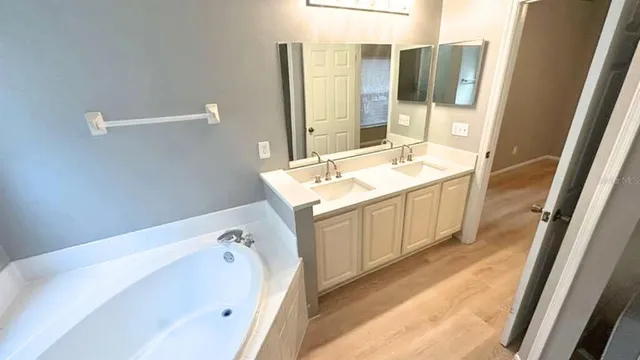 a spacious bathroom with a tub sink and mirror
