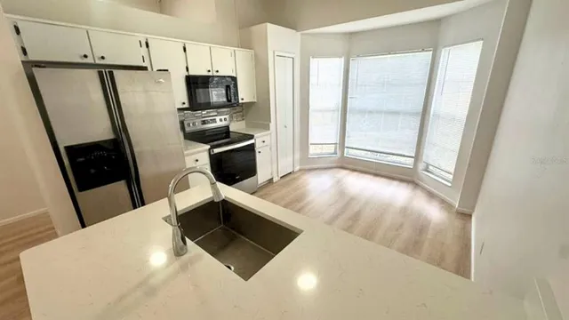 a kitchen with stainless steel appliances a refrigerator a sink a stove top oven a counter space and cabinets