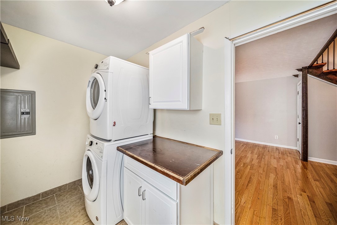 1796 Lander Road Mayfield Heights, OH 44124 - Photo 16 of 39 Clothes washing area featuring light hardwood / wood-style flooring, stacked washer and dryer, cabinets, and electric panel