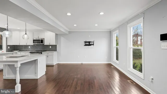 a large kitchen with stainless steel appliances granite countertop a stove a sink and white cabinets with wooden floor