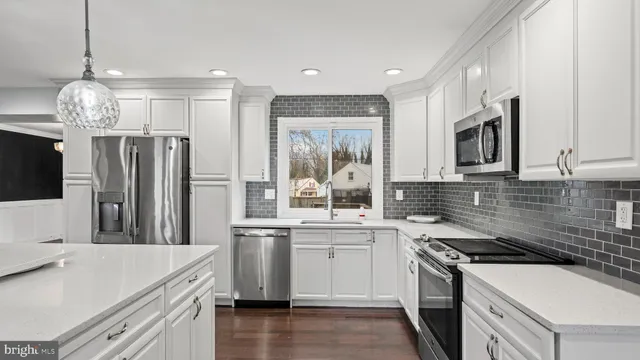 a kitchen that has a sink a stove top oven a refrigerator and a dining table with wooden floor