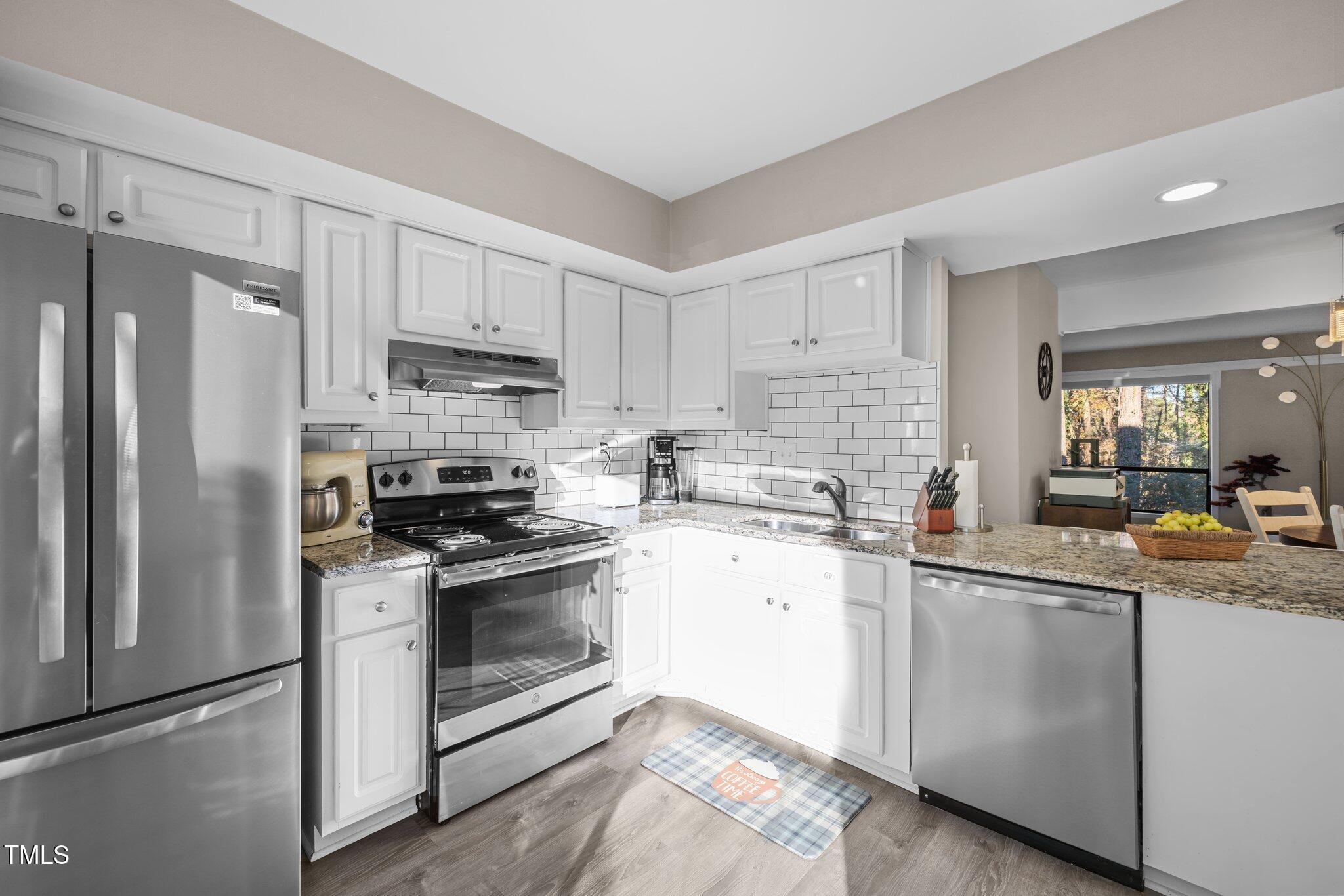 6230 Dixon Drive Raleigh, NC 27609 - Photo 5 of 32 a kitchen with stainless steel appliances granite countertop a sink a stove a refrigerator and white cabinets