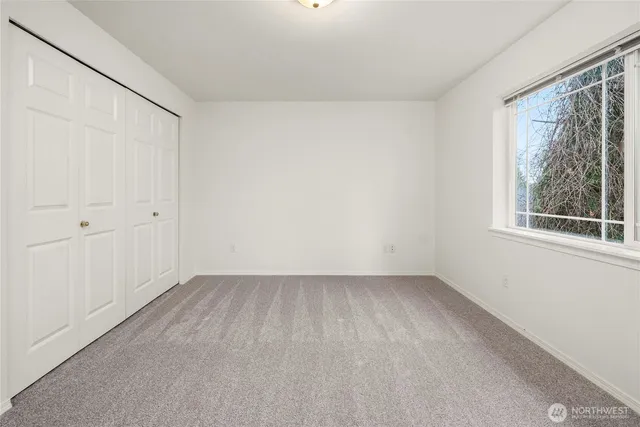 a view of an empty room with a window and hardwood floor
