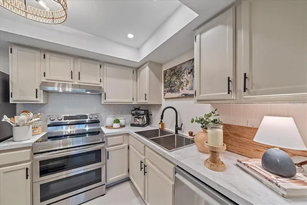 a kitchen with a sink dishwasher and white cabinets with wooden floor