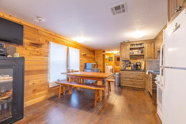 a living room with couches and kitchen view with wooden floor