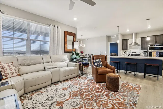 a living room with furniture a kitchen view and a large window