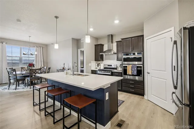 a kitchen with stainless steel appliances a stove a sink a refrigerator a center island and chairs