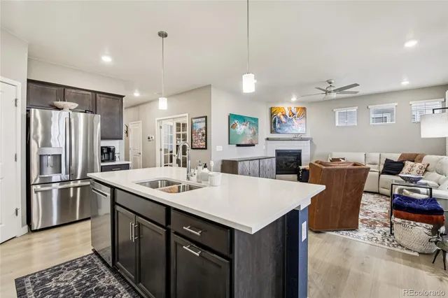 a kitchen with a refrigerator a stove a sink dishwasher a dining table and chairs with wooden floor