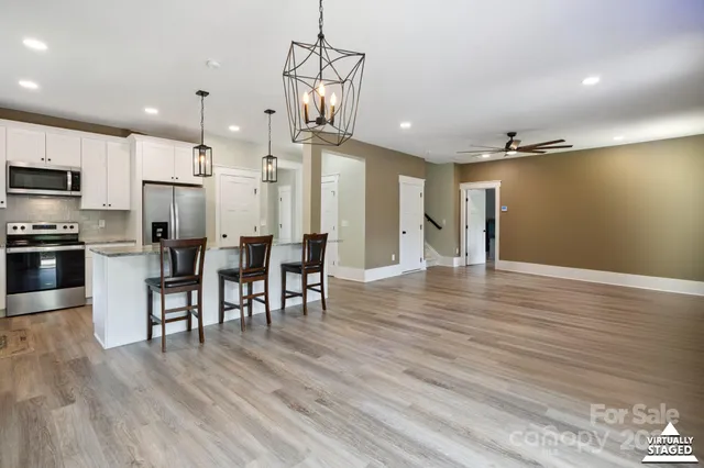 an empty room with wooden floor and kitchen view