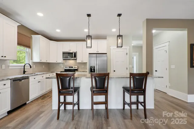 a kitchen with stainless steel appliances granite countertop a kitchen island hardwood floor sink and stove