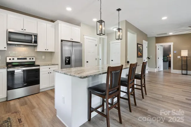 a kitchen with stainless steel appliances granite countertop a kitchen island hardwood floor and a sink