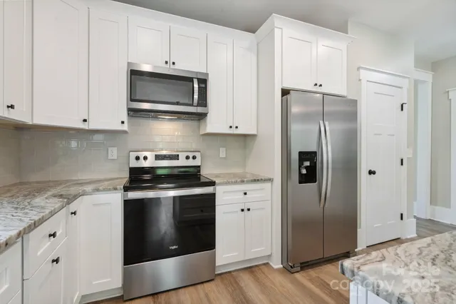 a kitchen with stainless steel appliances granite countertop a refrigerator stove and white cabinets
