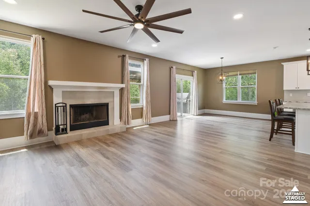 an empty room with windows fireplace and wooden floor