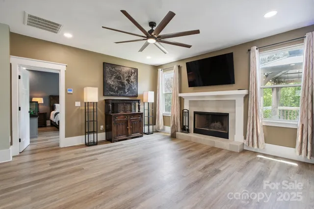 a view of a livingroom with a flat screen tv ceiling fan and a fireplace