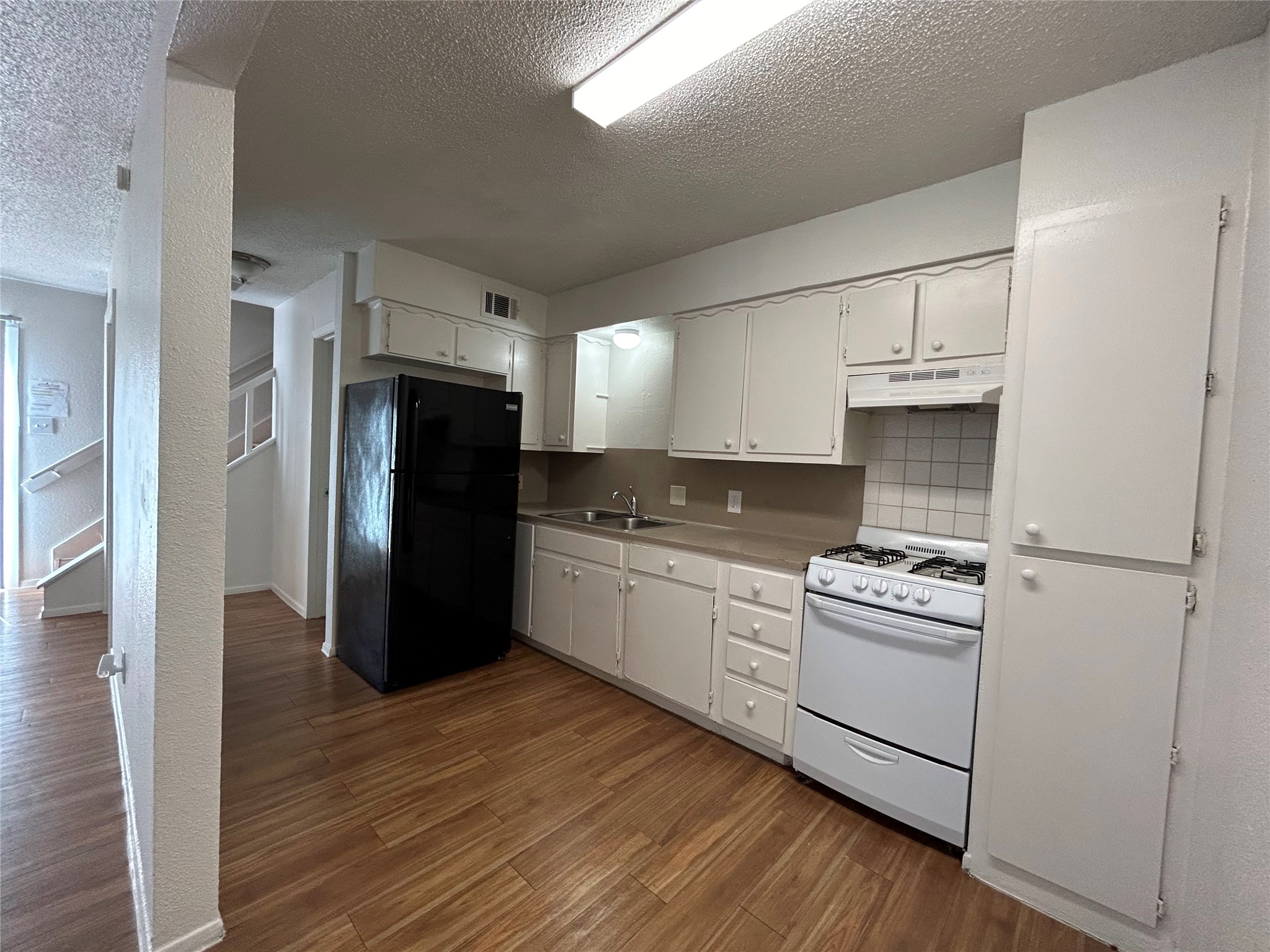 4810 West Wind Trail, Unit 104 Austin, TX 78745 - Photo 5 of 21 a kitchen with granite countertop a refrigerator and a stove top oven