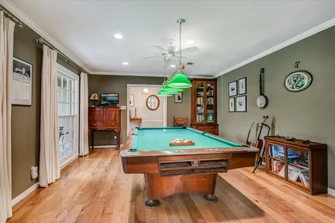 a room with furniture pool table wooden floor and window