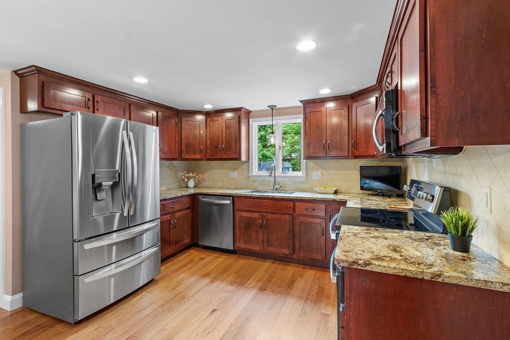 61 Pine Ridge Drive Franklin, MA 02038 - Photo 13 of 41 a kitchen with granite countertop wooden floors stainless steel appliances a sink and a window